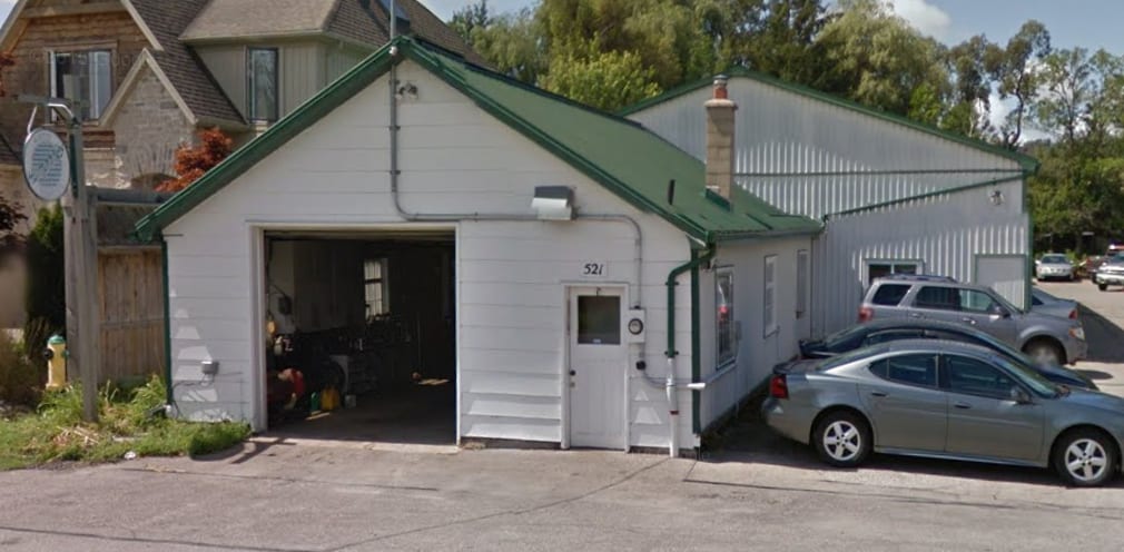 The front of the shop from the road: white siding, a green roof and the number 521 beside the door.