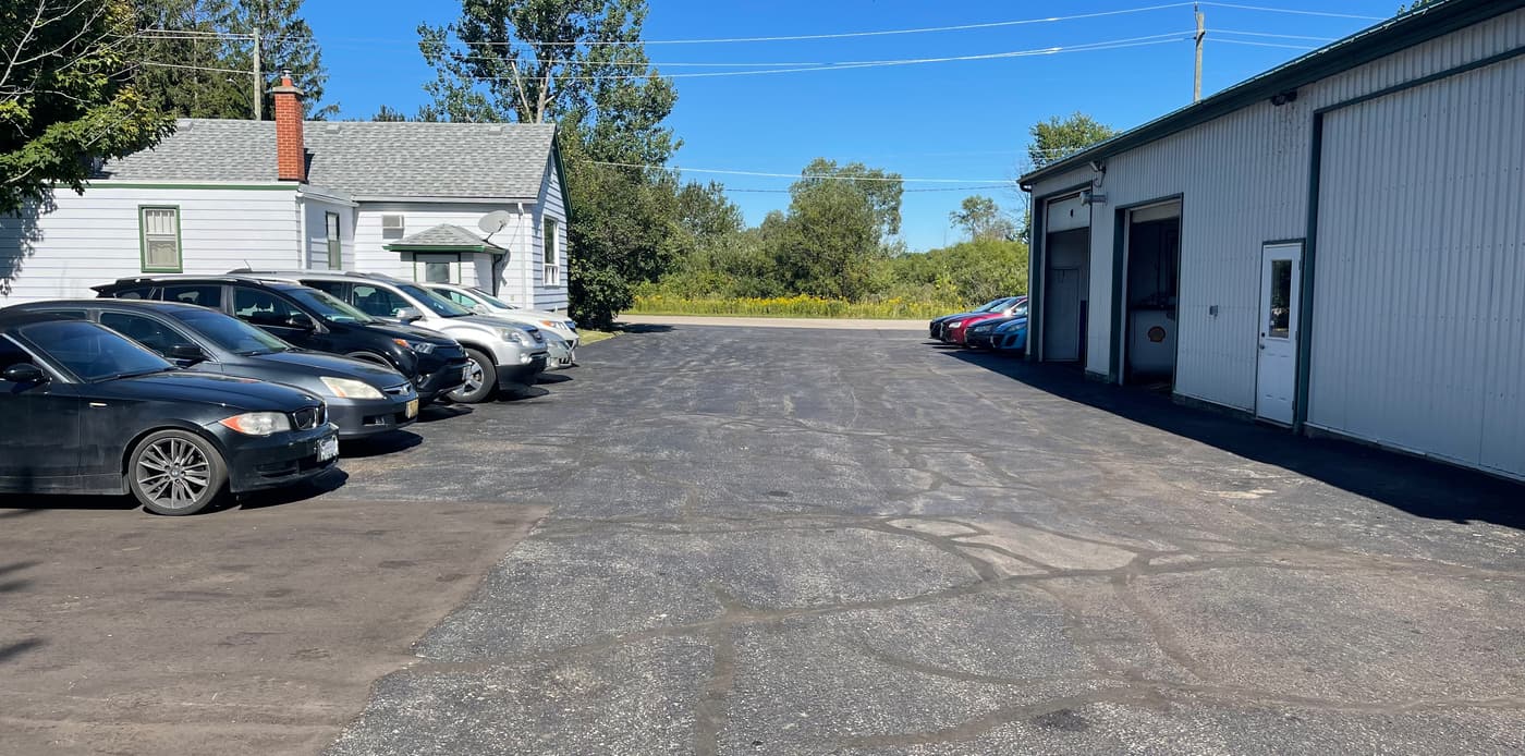 The yard at Humphries Auto Service on a sunny day: customer cars parked on the left and the service bays on the right.